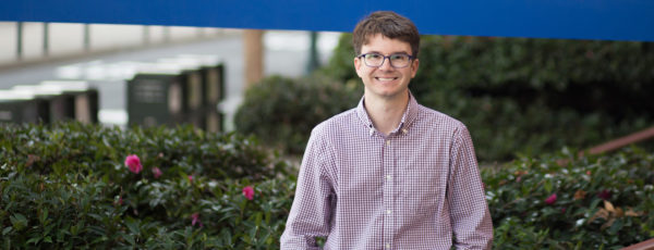 Jay Disser standing outside. He has short, brown hair and is wearing a purple-white shirt and glasses.