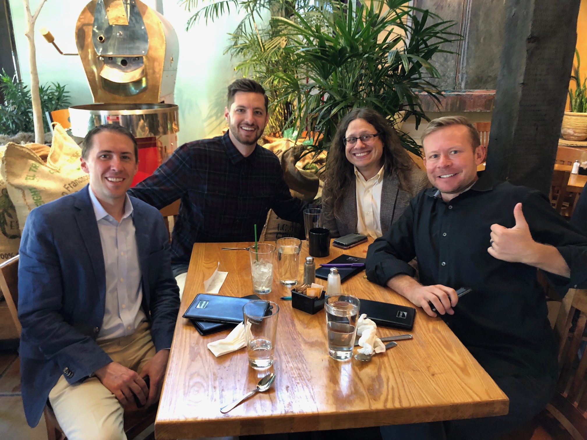 Four EMBAs sit around a brown table in a restaurant.