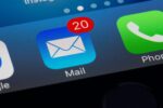 Close-up of a smartphone screen displaying app icons: Google, Mail with a notification badge showing 20, Phone, and WhatsApp.