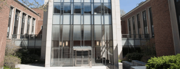 A modern building with large glass windows and brick walls, featuring a sign that reads 